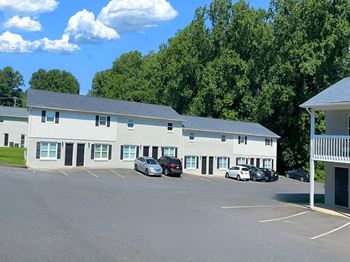 A parking lot with cars in front of a white building